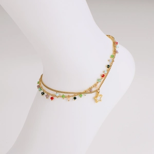 Double-layered gold star anklet with colorful beads on a white mannequin foot