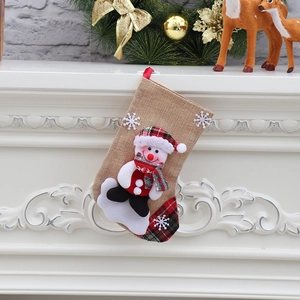Detail of burlap Christmas stocking with snowman doll hanging on a white fireplace