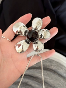 Macro shot of large metallic flower pendant with a brown resin stone on a snake chain