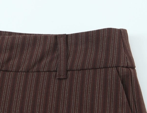 Detail of the high-waisted deep red trousers showing vertical pinstripes and belt loop