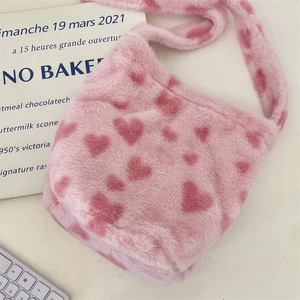 Detail of soft pink faux fur shoulder bag featuring heart pattern and plush strap texture