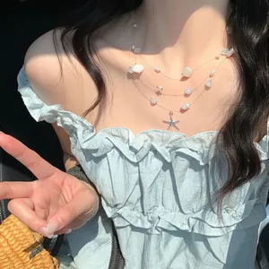 Three-layer summer necklace with starfish shell charms and blue beads on a model