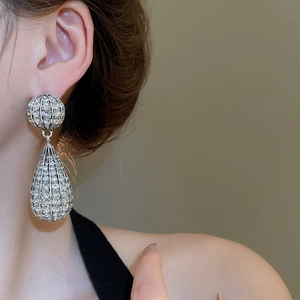 Close-up of sparkling silver water-drop earrings with crystals worn by a model