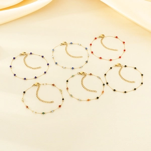 Set of six gold beaded bracelets with colorful charms on elegant beige silk fabric