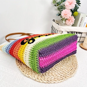 Detail view of colorful rainbow straw tote bag with brown handles and black S embroidery