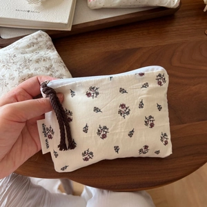 Detail of floral cotton mini pouch with zipper and simple wish label on wood surface