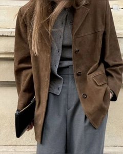 Close-up of vintage brown suede jacket with lapel and pocket detailing in urban setting