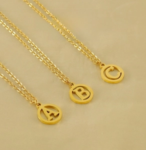 Vue détaillée de trois colliers circulaires creux plaqués or 18K avec lettres A B C