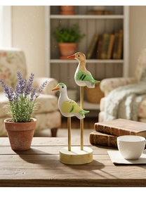 Detail of minimalist wooden seabird statues on stands with hand-painted colorful accents