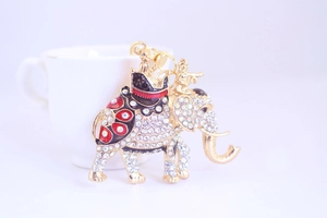 Macro detail of golden elephant keychain with sparkling rhinestones on a white cup