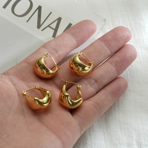 Chubby oval pea gold stainless steel earrings shown in hand for size and texture detail