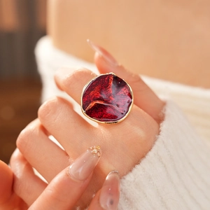 Detail of vintage red enamel ring with gold wavy trim worn on a model's hand