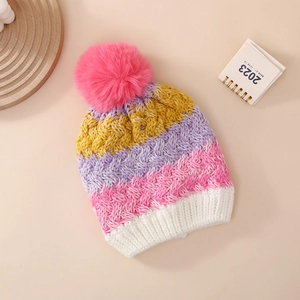 Detailed knit texture of children's colorful striped beanie with a fluffy pompom top