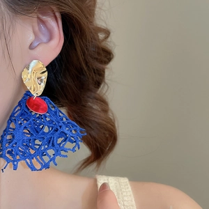 Close-up of elegant long fringe earrings with blue lace petals and gold metal accents