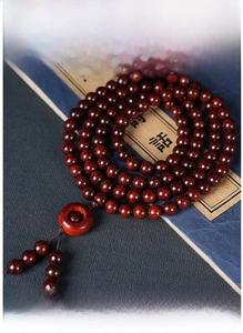 Detailed view of 108 sandalwood prayer beads with rotatable charm and red tassel