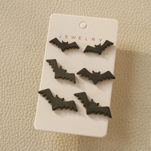 Three pairs of matte black bat stud earrings on white display card for Halloween