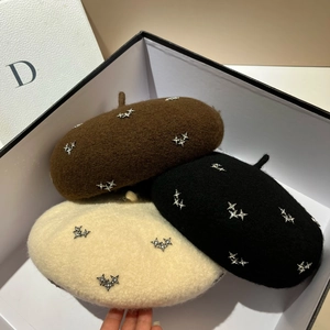Detailed top view of wool berets in brown, black, and beige with rhinestone star accents