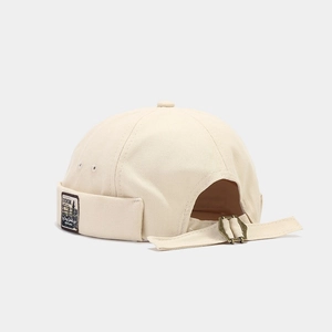 Detail of off-white brimless beanie with retro side label and metal buckle adjustment