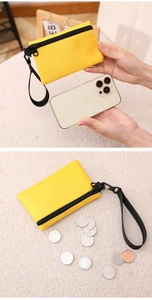 Porte-monnaie jaune en polyester avec dragonne montrant la taille par rapport à l'iPhone
