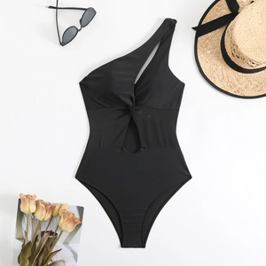 Flat lay of black one shoulder swimsuit with cut-out detail and summer vacation props