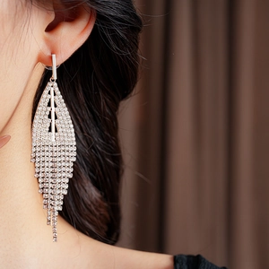 Close-up of sparkling gold tassel earrings with leaf-shaped rhinestone fringe on model