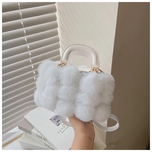 Close-up of white plush handbag with fluffy texture, leather handle and gold hardware detail
