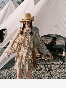 Outdoor lifestyle shot of a women's floral long sleeve dress with a straw sun hat