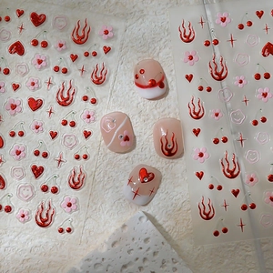 Detail of red heart and flame nail art stickers with 3D metallic texture effects