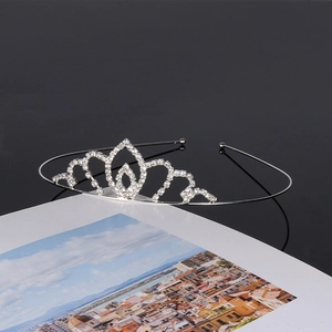 Detailed view of silver rhinestone tiara with wavy design on a black reflective surface