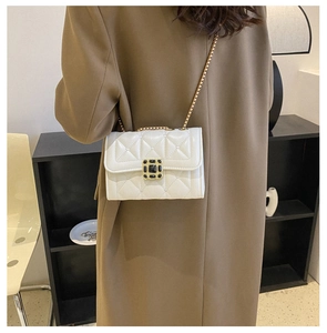 Detail of white quilted crossbody bag with gold chain and black gemstone buckle