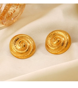 Gros plan de boucles d'oreilles spirales dorées avec texture métallique sur tissu beige