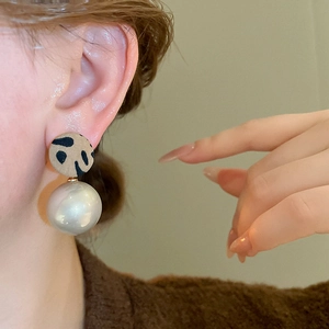 Détail macro de boucles d'oreilles léopard rondes avec une grande perle blanche pendante