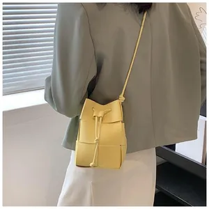 Detailed view of a yellow woven bucket bag with drawstring closure on a shoulder strap