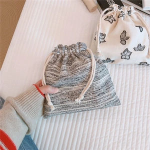 Detail showing natural linen drawstring bag texture and floral pattern for storage
