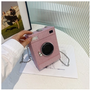 Pink glitter camera shaped crossbody bag with silver chain strap and circular lens detail