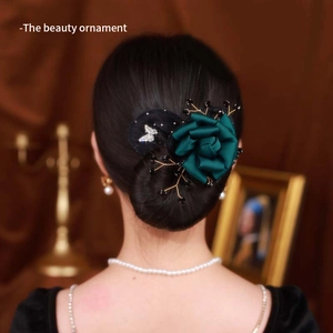 Detail of dark green satin rose hair accessory with butterfly accent on woman hair