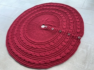 Close-up of red cable knit Christmas tree skirt with classic cable patterns and buttons