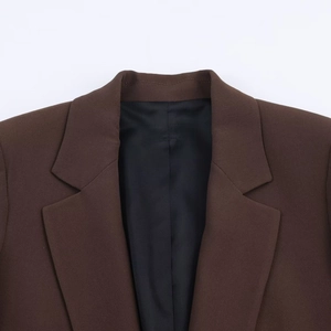 Detail shot of notched lapel and fine fabric texture on dark brown blazer