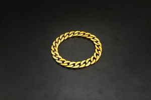 Macro shot of thick gold-plated cuban link bracelet with high-polish metallic finish