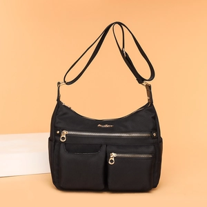 Waterproof nylon crossbody bag with multiple pockets and gold zippers on a warm background