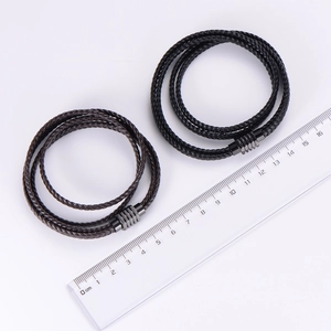 Detail view of multilayer braided leather bracelets in black and brown with magnetic clasp