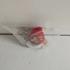Close-up of a Christmas gnome plush in transparent packaging with red hat and gingerbread man