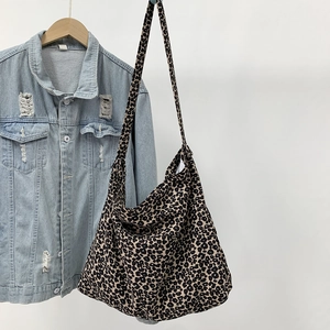 Detail view of stylish leopard print canvas tote bag hanging next to denim jacket