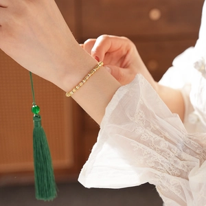 Close-up of 18k gold plated bracelet with zircon beads on a wrist with lace sleeve