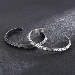 Detailed view of silver titanium steel cuffs with diamond lattice textures and engraving