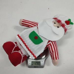 Nahaufnahme einer Weihnachts-Koch-Wichtel-Puppe beim Wiegen auf einer Digitalwaage