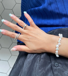 Detail of layered S925 silver minimalist line rings and baroque pearl bracelet on hand