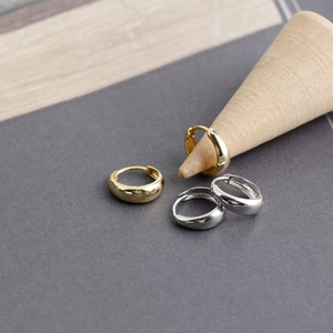 Polished S925 silver hoop earrings in gold and silver finish on a wooden display