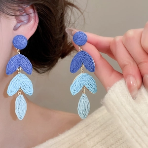 Detail of blue gradient raffia tassel earrings with three leaf-shaped woven layers