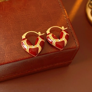 Macro detail of gold plated heart hoop earring with red enamel and pavé crystals